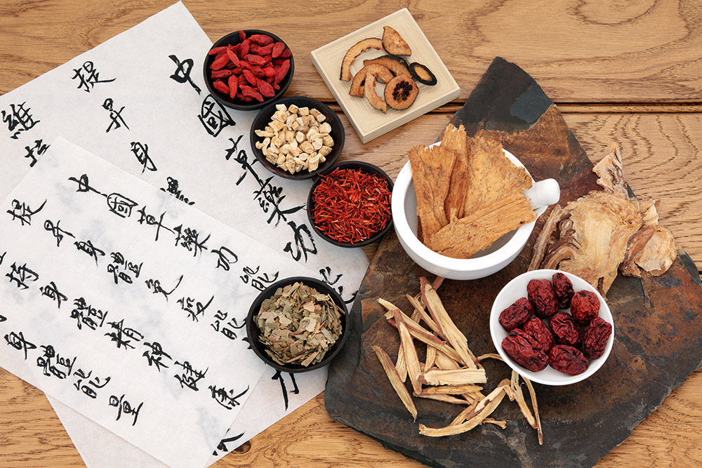 Traditional chinese herbal medicine selection with mandarin calligraphy on rice paper over oak. Translation describes the medicinal functions to maintain body and spirit health and balance energy.